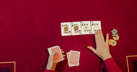 Playing cards on a red table in casino. Close-up of hands.