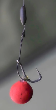 Fishing hook with a red float on a gray background, close-up