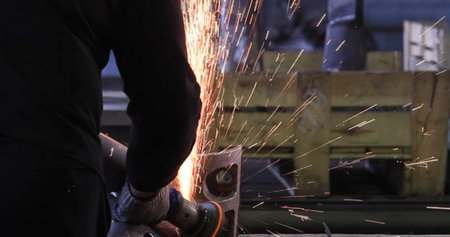 Industrial worker cutting metal with angle grinder. Sparks while grinding iron.