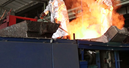 Worker in a metallurgical plant working with molten metal.