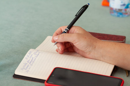 Hand holding pen while writing in notebook
