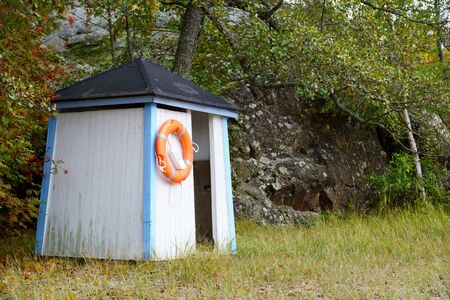 A beach cabin decorated with a lifebuoy, waiting for a new summer season of swimming and entertainment, stands alone on the beach.の写真素材