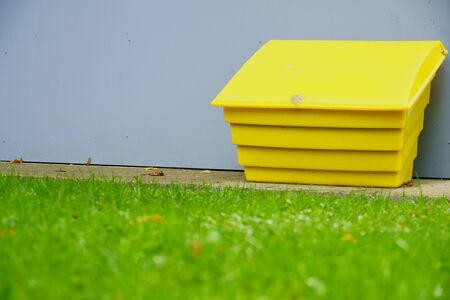Yellow sandbox on the background of a gray basement of the house. In front of the house is a beautiful green lawn with autumn leaves. copy spaceの写真素材