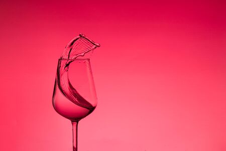beautiful splashes of water in a wine glass, with red filter, close up with copy space.