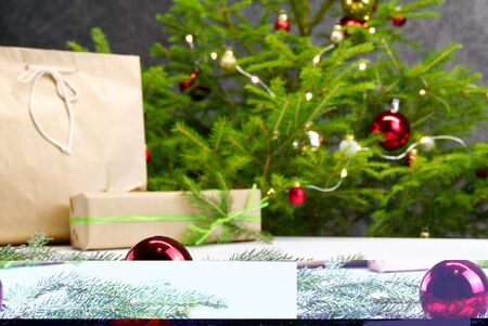 Beautiful Christmas composition. Gift boxes and christmas tree with lights on background. Decoration red ball with spruce branch. Xmas backdrop for your greeting card with space for text. Photoの写真素材
