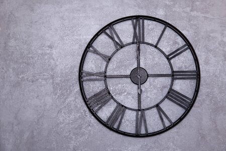 Vintage wall clock with roman numerals on the wall. gray stucco wall. The clock shows twelve 12:00の写真素材