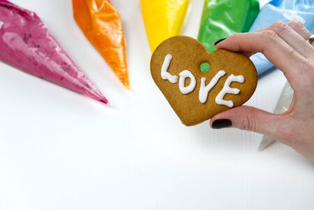 Christmas gingerbread cookies in hand with colored sweet icing. gingerbread cookies with white text Loveの写真素材