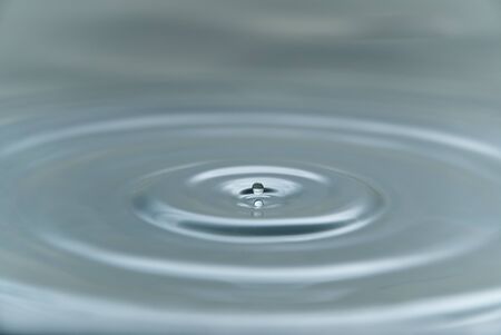 a small drop of water hovering in the air before hitting a water surface and make spash , a...