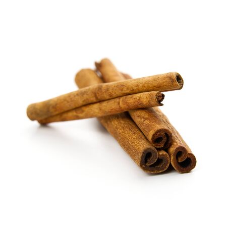 three cinnamon sticks stacked on white background.