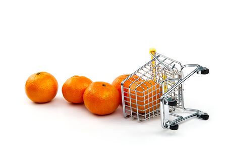 A mandarin in shopping cart isolated on white background. Ripe tasty tangerines in shopping cart. Mandarin trading concept. Online shopping concept. Cart and mandarins over a white background. business concept. Healthy eating concept.の写真素材