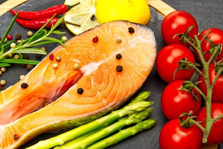 Fresh salmon steaks with aromatic herbs, spices, peppers and lemon. Healthy food, diet or cooking concept.の写真素材
