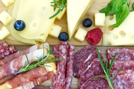 Beautiful sliced food arrangement close-up photo. Italian style antipasto plate, cheese, ham, salami, rosmarin, prosciuttoの写真素材