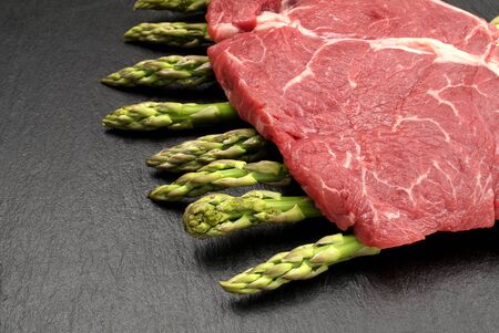meat food : raw beef fillet on black stone board with asparagusの写真素材