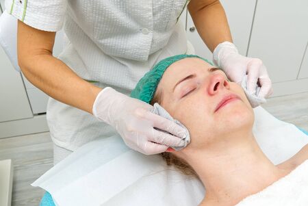 Beautician cleans face. Young woman in a beauty salon. Cosmetology concept. The cosmetologist...