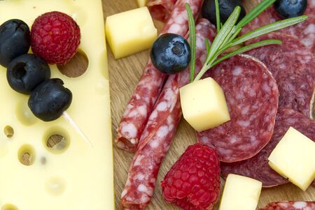 Meat and cheese plate antipasti snack with Prosciutto ham, Parmesan, Blue cheese, Cantaloupe melon and Olives on olive wood serving board on dark stone backgroundの写真素材