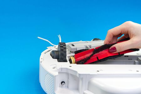 white robot vacuum cleaner on a blue background. The procedure for cleaning the robot vacuum cleaner...