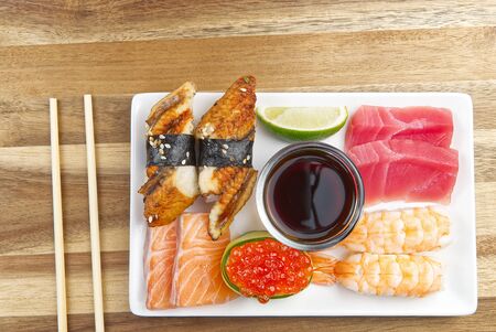 traditional japanese sushi set on a white plate with wood background. tasty set of sushi, nigiri, sahimi and maki. delicious dinner or lunch for one person. flat layの写真素材