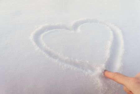 heart drawing by hand on fresh snowの写真素材