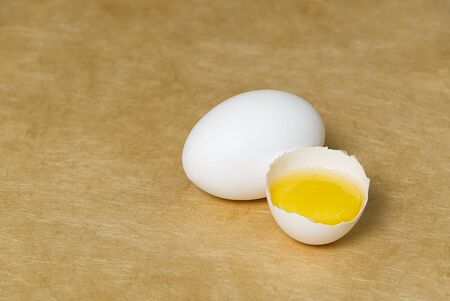 chicken white eggs with half broken egg on beige textured background