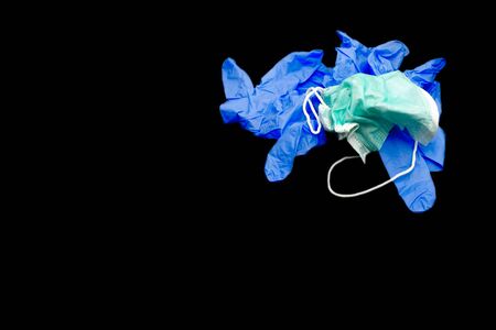 used surgical face mask and medical gloves on black background with copy space. Used antivirus face...