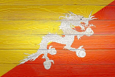 Bhutan flag painted on old wood plank background. Brushed natural light knotted wooden board texture. Wooden texture background flag of Bhutan.の写真素材