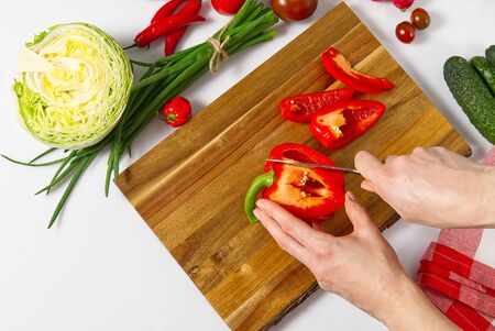 salad from fresh vegetables in a plate on a table. bowl of salad with vegetables and greens on white table. Women preparing vegetable salad- close up shot. Domestic kitchen. Vegetarian food.の写真素材