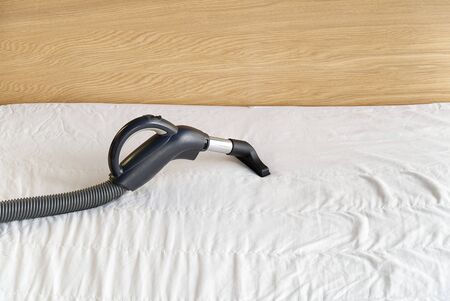 Vacuuming bed. Domestic home cleaning concept. Textile sofa chemical cleaning. Upholstered furniture. Early spring cleaning or regular clean up. Cleaning Service conceptatHome, apartments, hotelsの写真素材