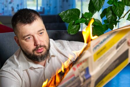 businessman reading hot news or reading stock market news share prices. Burning magazine in mans hands - hot and breaking news conceptの写真素材