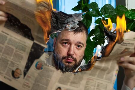 businessman reading hot news or reading stock market news share prices. Burning magazine in mans hands - hot and breaking news conceptの写真素材
