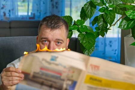 businessman reading hot news or reading stock market news share prices. Burning magazine in mans hands - hot and breaking news conceptの写真素材