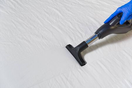 Vacuuming bed. Domestic home cleaning concept. Textile sofa chemical cleaning. Upholstered furniture. Early spring cleaning or regular clean up. Cleaning Service conceptatHome, apartments, hotelsの写真素材