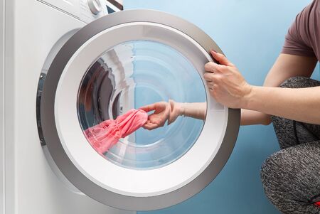 girl takes out the laundry from the washing machine. woman puts clothes in a washing machine