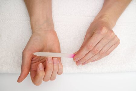 woman filing her finger at home. female polishes her nailsの写真素材