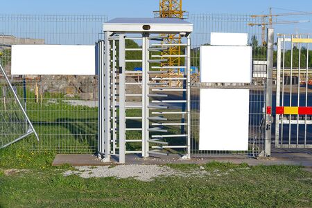 electronic access gates to the construction site. white plates for ad text or security...