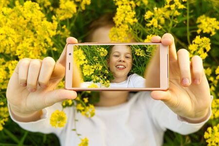 Happy smiling boy making self portrait on smartphone in meadow. young boy making selfie on...