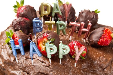 homemade chocolate cake with strawberries and happy birthday candles, close-up.の写真素材