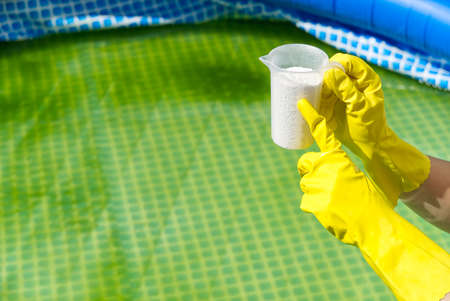 addition of chlorine powder for the pool to remove algae and disinfect water. inflatable swimming pool care concept.の写真素材