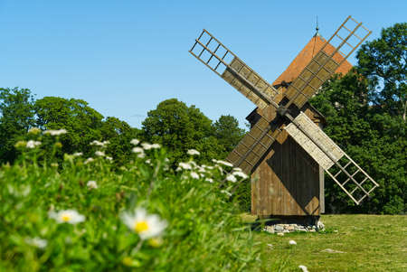Old vintage wooden windmill in the background of the summer field. Saaremaa, Estonia.の写真素材