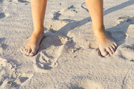 Close-up of children legs on sand beach. Young girl legs on baltic sea beach. Teenager legs in sand.