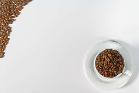 Coffee beans in white cup, close-up. White coffee cup with coffee seeds on white background. Concept For International day of coffee.の写真素材