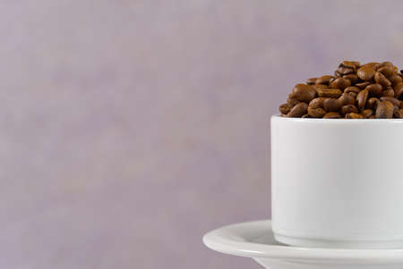 International day of coffee concept. close-up white coffee cup full of coffee beans on old rose...