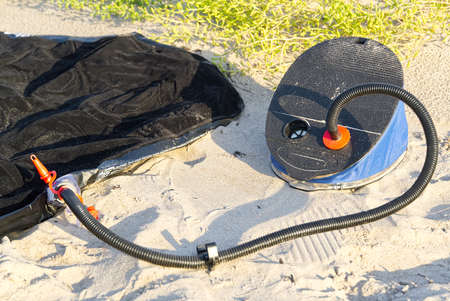 Foot pump near inflatable mattress or air bed at sandy beach. inflates air mattress with foot pump on sand.の写真素材