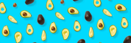 Avocado banner. Background made from isolated Avocado pieces on blue background. Flat lay of fresh ripe avocados and avacado piecesの写真素材