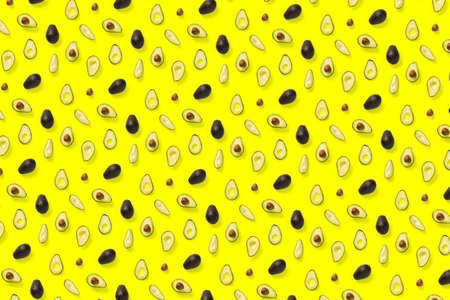 Avocado. Background made from isolated Avocado pieces on yellow background. Flat lay of fresh ripe avocados and avacado piecesの写真素材