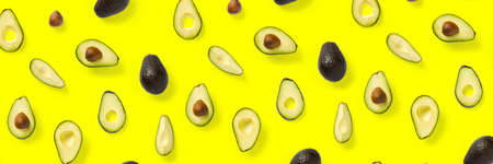 Avocado banner. Background made from isolated Avocado pieces on yellow background. Flat lay of fresh ripe avocados and avacado piecesの写真素材