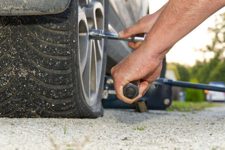 Man changing wheel. tire changer changing flat car tire. Mechanic hands unscrews a flat tire of a...
