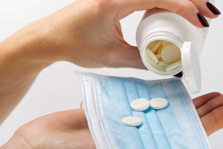 concept covid vaccine pills. COVID-19. Medical mask on a hand with white background. Medicine pills...