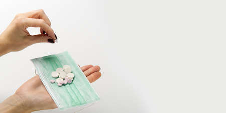 Medical mask on a hand with white background. Medicine pills or Vaccine against the virus. Hand holds medical face mask and white pills.の写真素材
