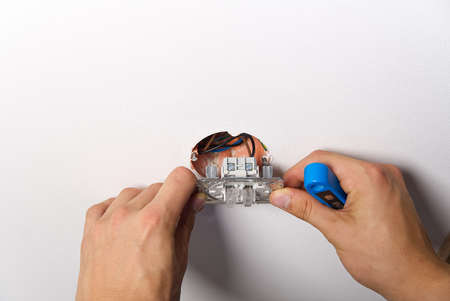 Man installing light switch after home renovation. Electrician installing light switch on painted...