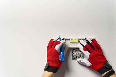 Man installing light switch after home renovation. Electrician installing light switch on painted wall with screwdriver.の写真素材